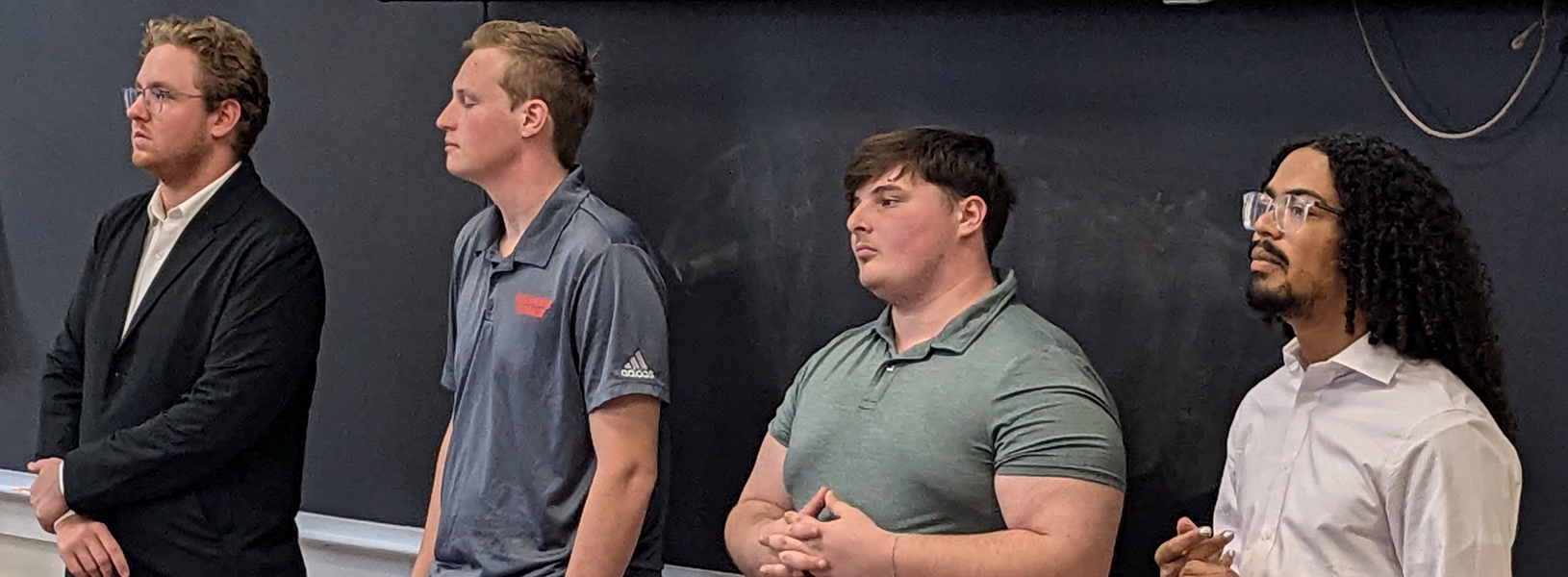 Four students at the blackboard presenting in a classroom.