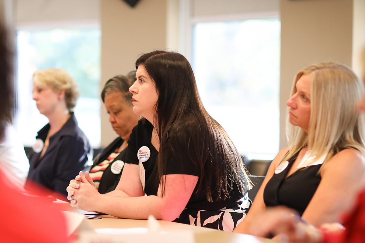 a woman talking to a group seated at a table