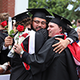 two men in graduation gowns and caps hugging