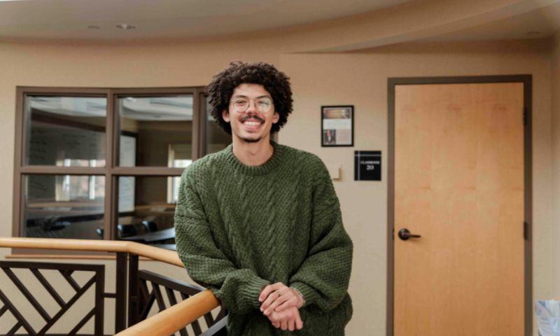 a man with curly hair and mustache wearing a green sweater