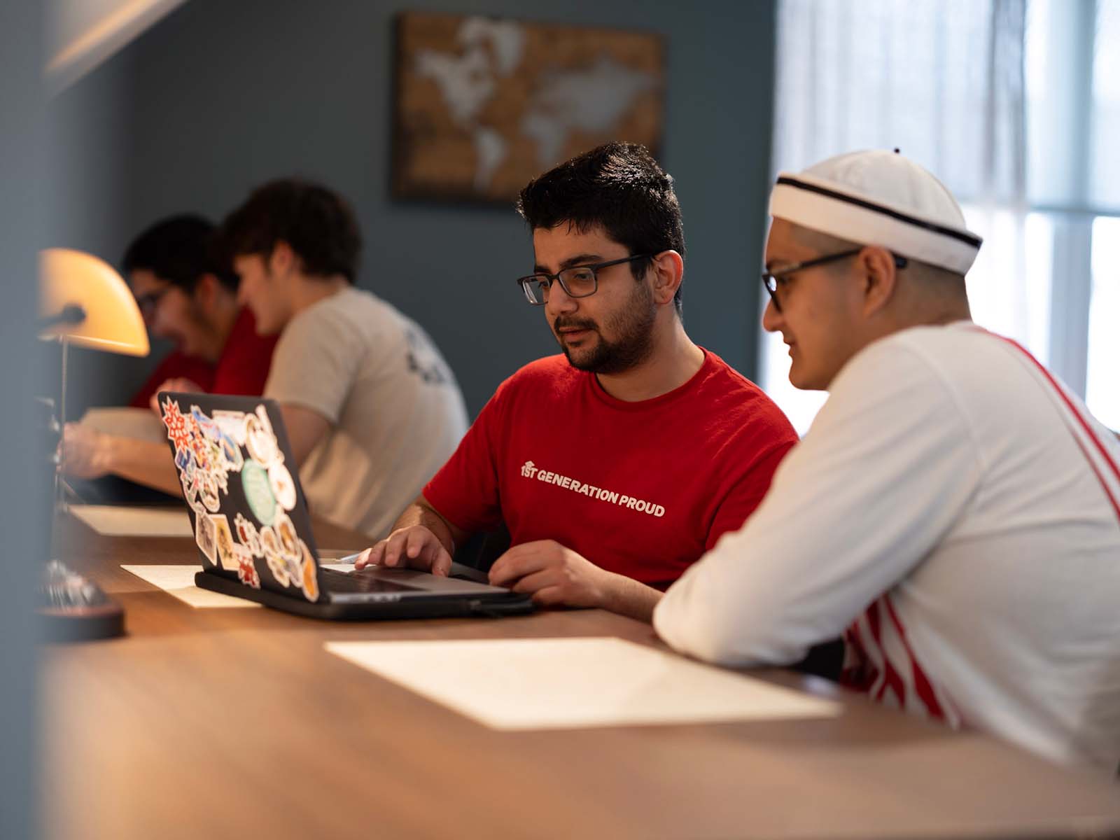 a group of men sitting at a table using a laptop