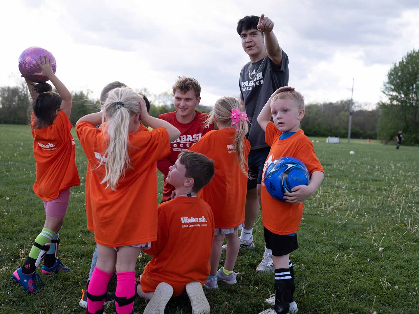 a group of kids in orange shirts standing on grass