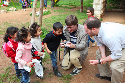 Philip Eubanks ’06 (holding camera) and his colleague showing photos to Syrian refugees.