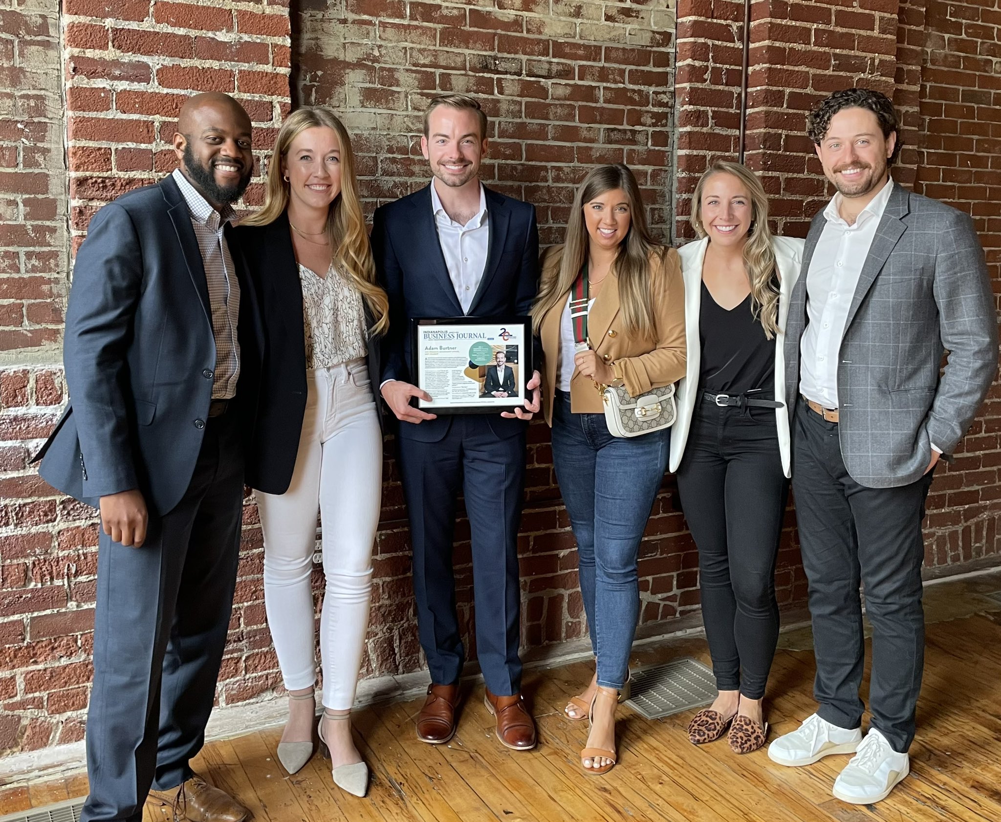 Adam Burtner ’17 (center) shows off his 20 in their Twenties plaque awarded by the Indianapolis Business Journal.  