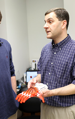 Professor Lon Porter (right) displays a prosthetic hand.