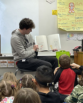 Schreiber reads a book with students. 