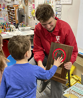 Watson shows the NCAC trophy to a student.