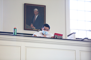 A student sits in the balcony in front of a presidential portrait.