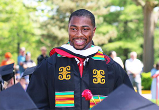 A graduate searches for family members to share smiles before sitting back in his seat.
