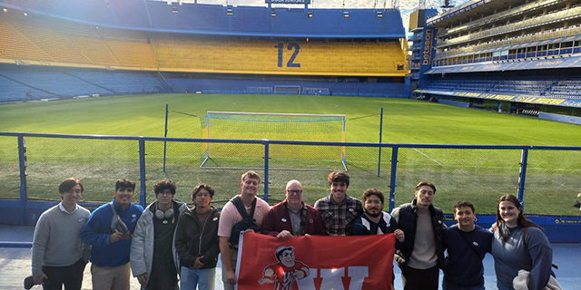Class poses for a photo in front of the pitch at Boca Juniors' stadium.