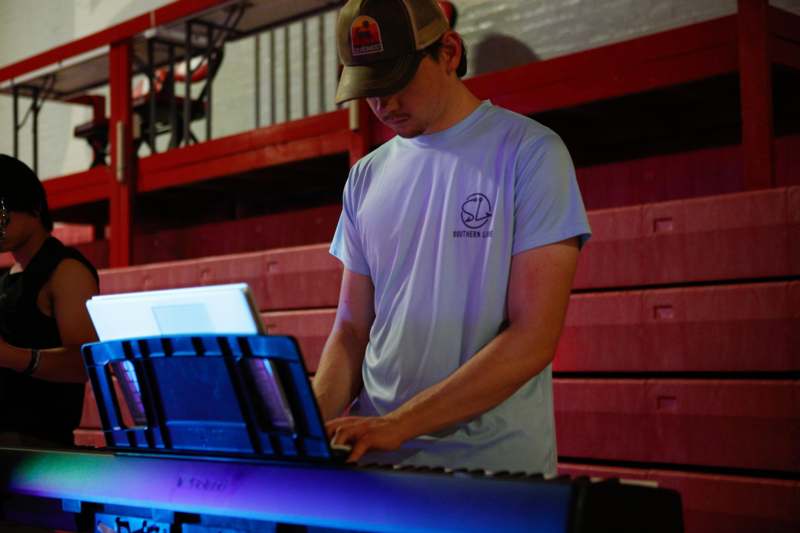 a man in a baseball cap playing piano