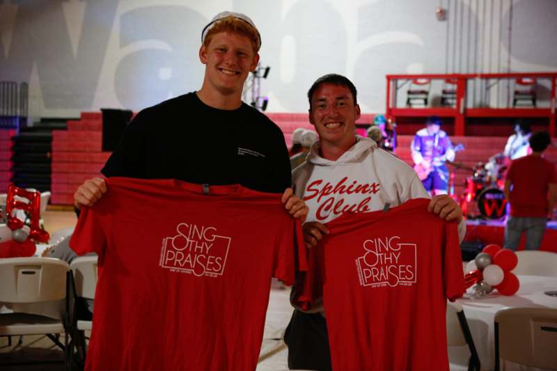 two men holding up red shirts