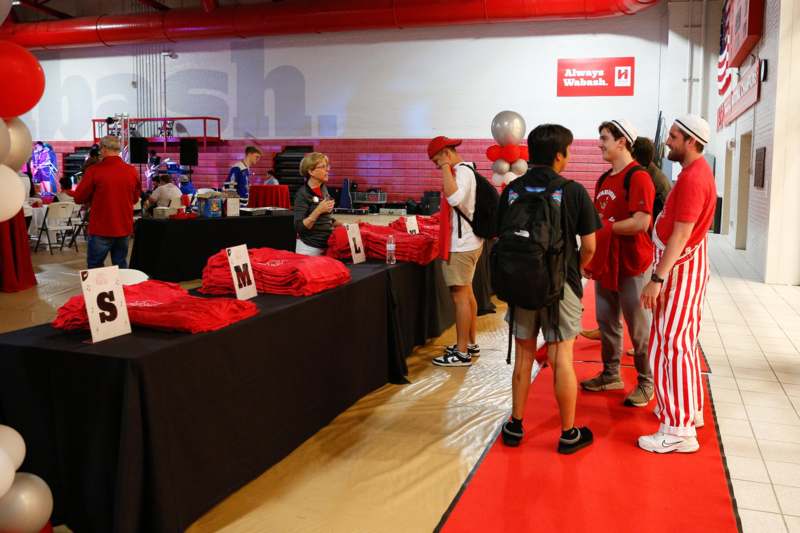a group of people standing in a room with red and black cloths