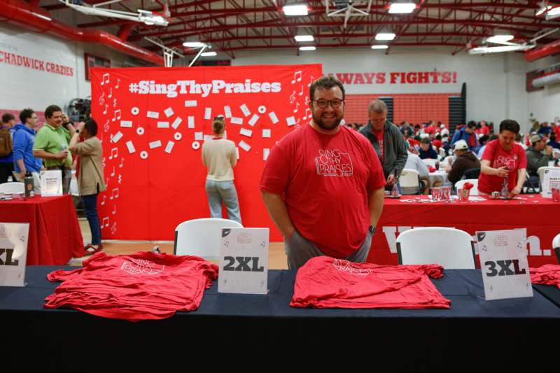 a man standing in front of a table with red shirts