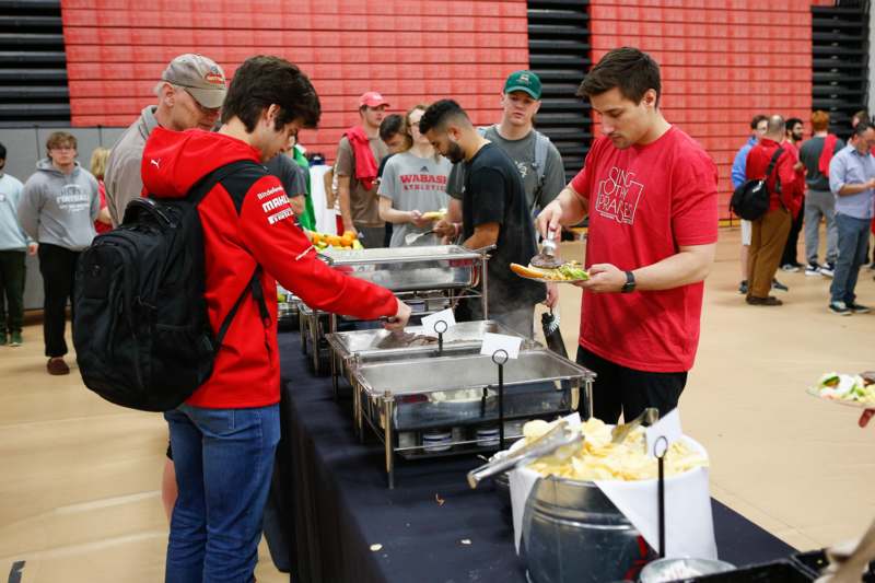 a group of people standing around a table full of food