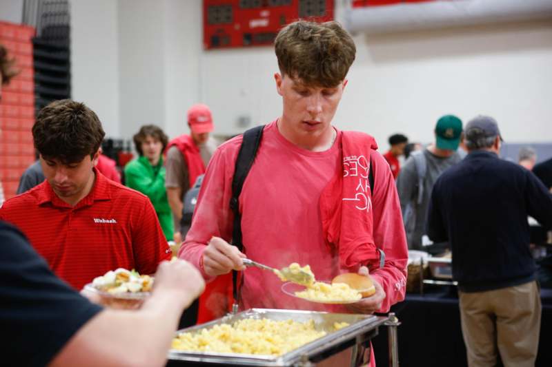 a man in a red shirt eating food from a tray
