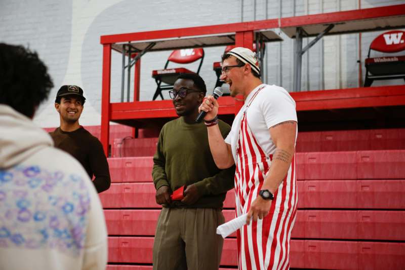 a man in a striped overalls holding a microphone and standing next to a man in a red and white striped overalls