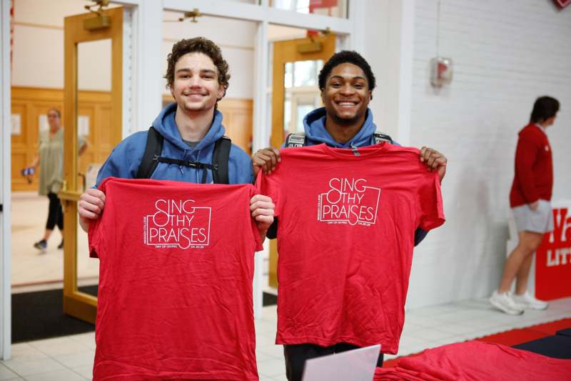 two men holding up red shirts