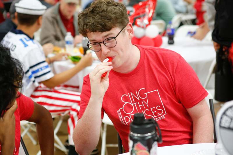 a man in a red shirt blowing a red balloon