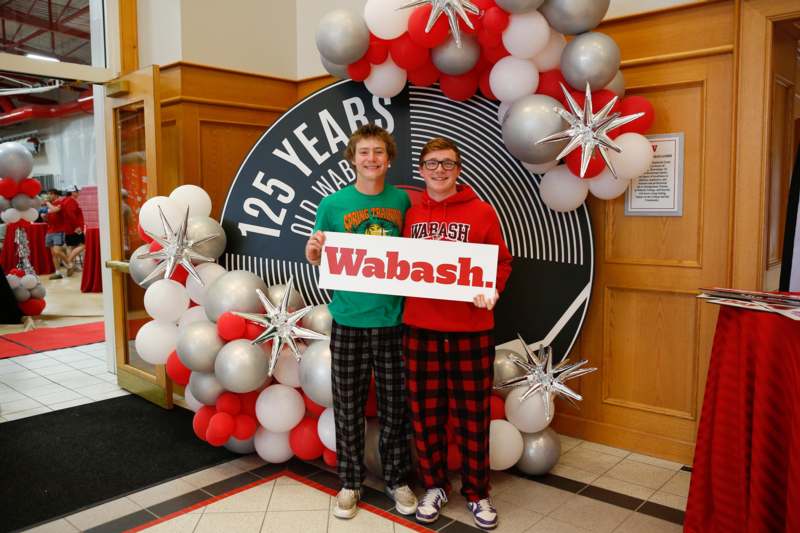 two men standing in front of a balloon arch