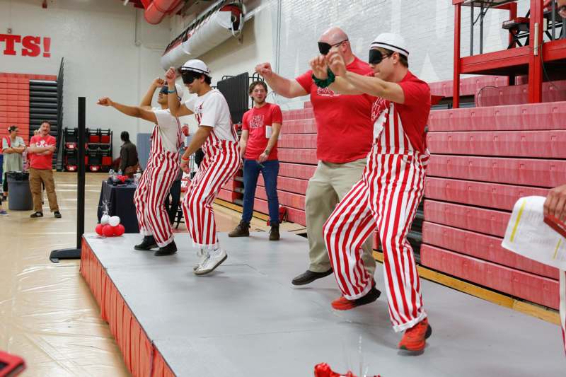 a group of men wearing striped pants and sunglasses dancing
