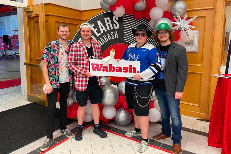a group of men standing in front of a balloon arch