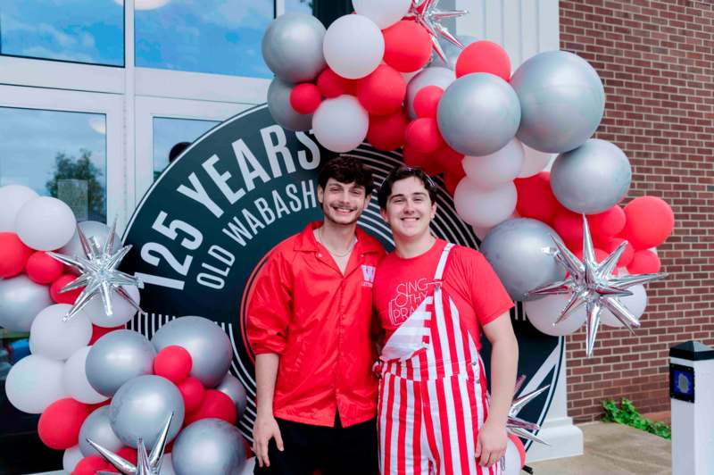 two men standing in front of a building with balloons