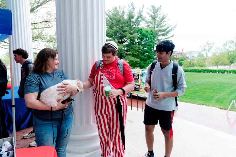 a group of people standing outside with a dog and a woman