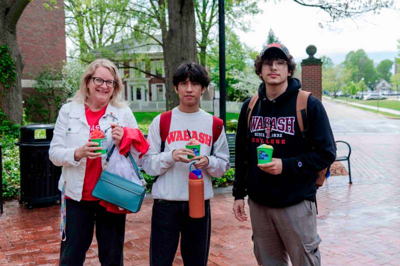 a group of people standing on a brick sidewalk holding cups