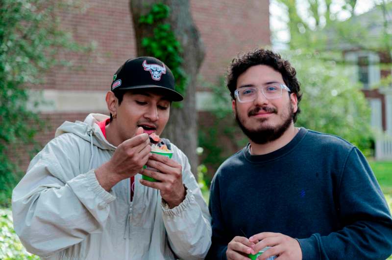 two men eating food outside