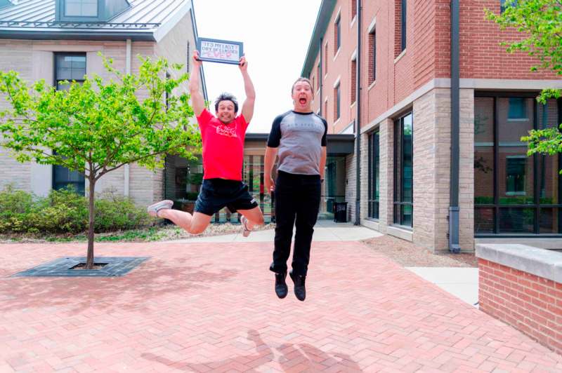 two men jumping in the air with a sign