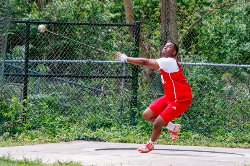 a man in red uniform hitting a ball with a stick