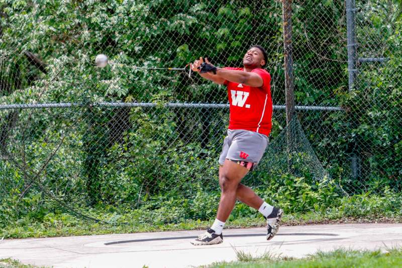 a man in a red shirt hitting a ball with a stick