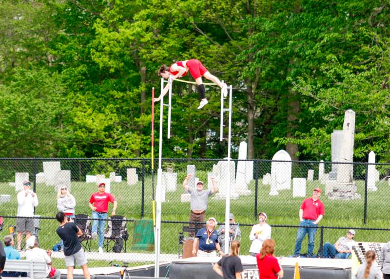 a woman jumping over a pole