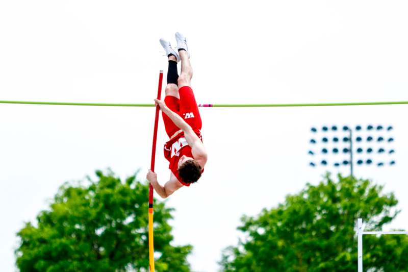 a man in red shorts jumping over a bar