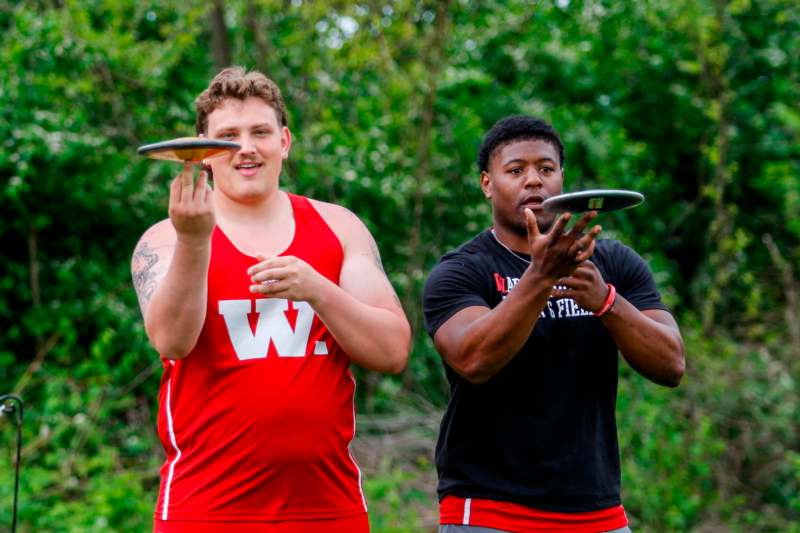 two men holding frisbees in their hands