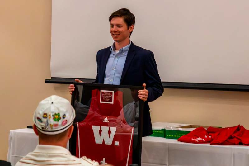 a man holding a framed picture of a jersey