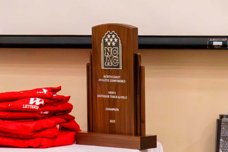 a wooden plaque with a logo and a stack of red shirts