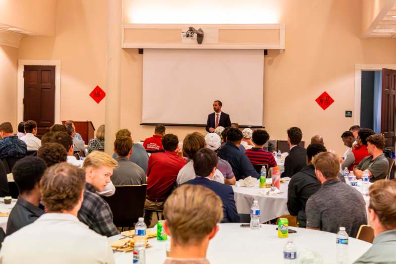 a man standing in front of a group of people seated at tables