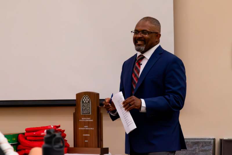 a man in a suit holding a piece of paper and a trophy