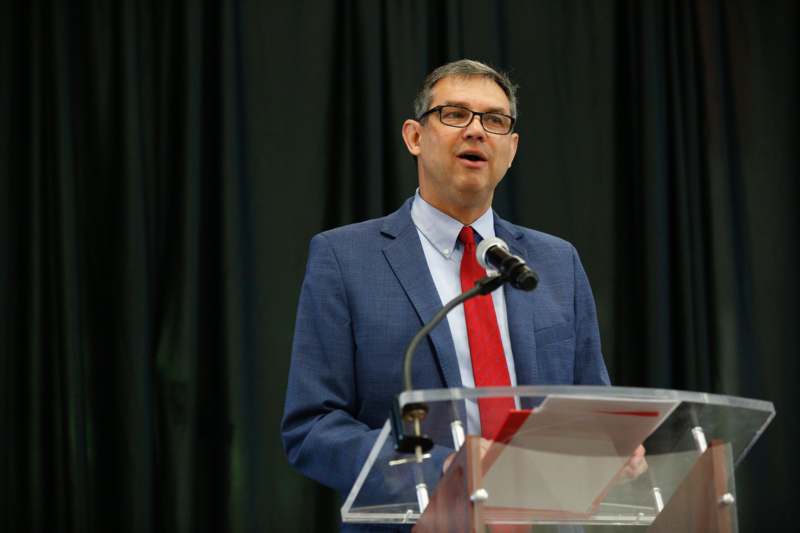 a man standing at a podium with microphones