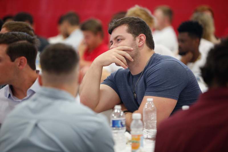 a man sitting at a table with a hand on his chin