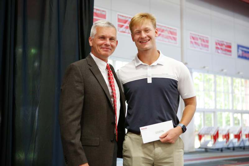 a man standing next to a man holding a piece of paper