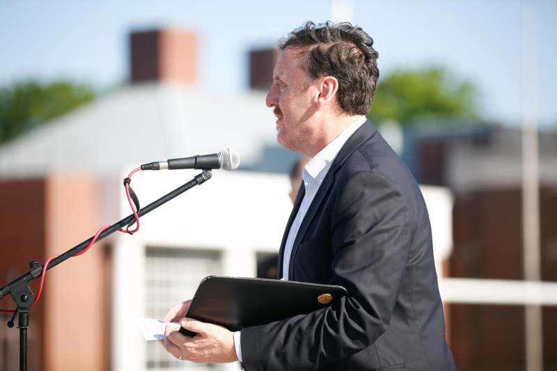 a man in a suit holding a clipboard and a microphone