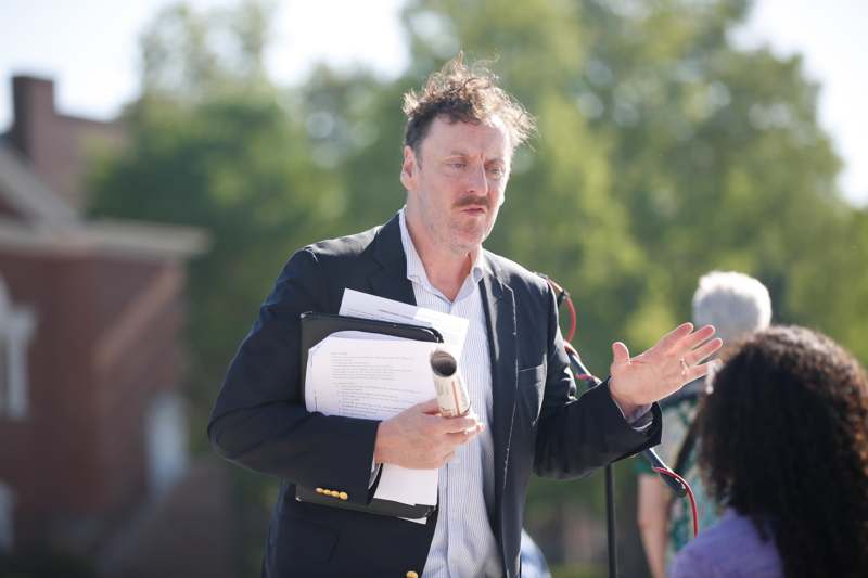 a man in a suit holding a folder and a paper