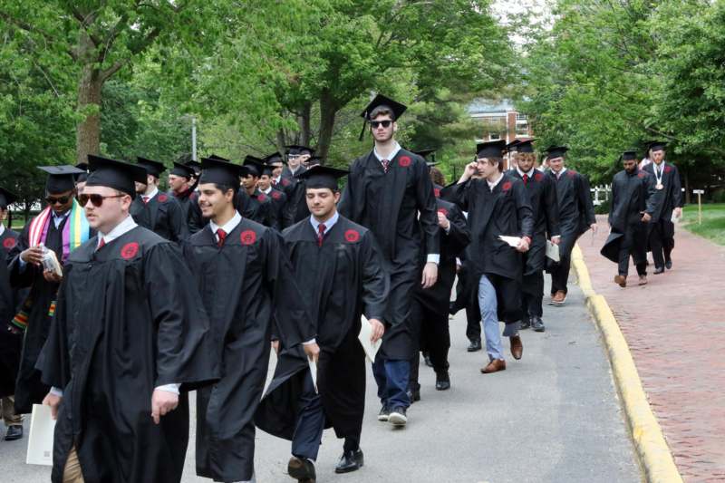 a group of people in graduation gowns walking down a sidewalk