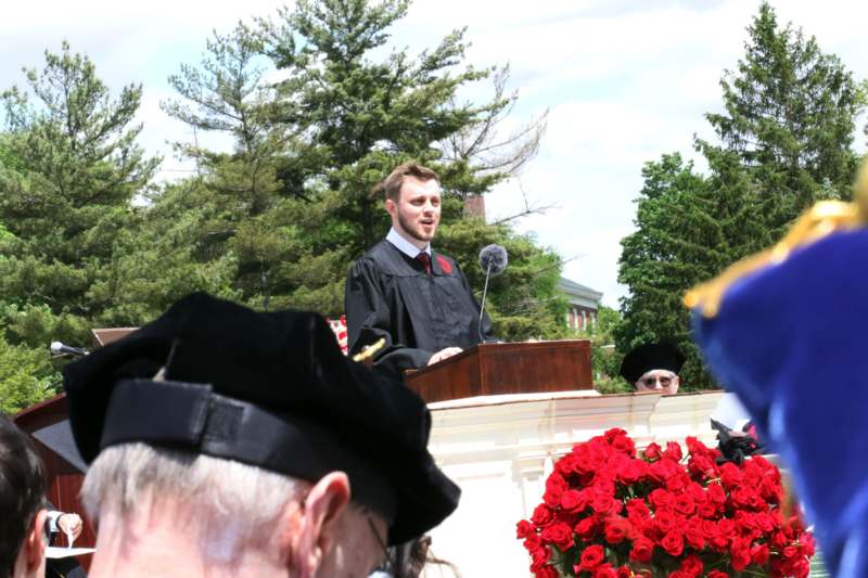 a man in a black robe standing at a podium with a microphone