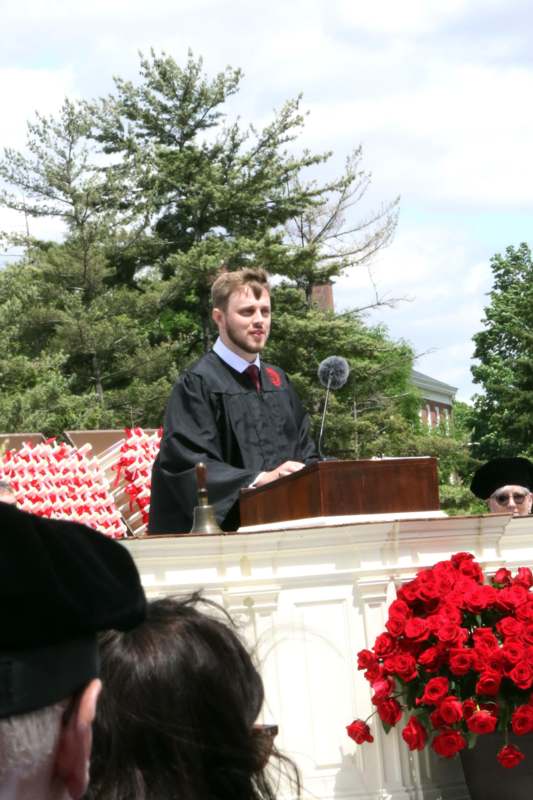 a man in a graduation gown standing at a podium