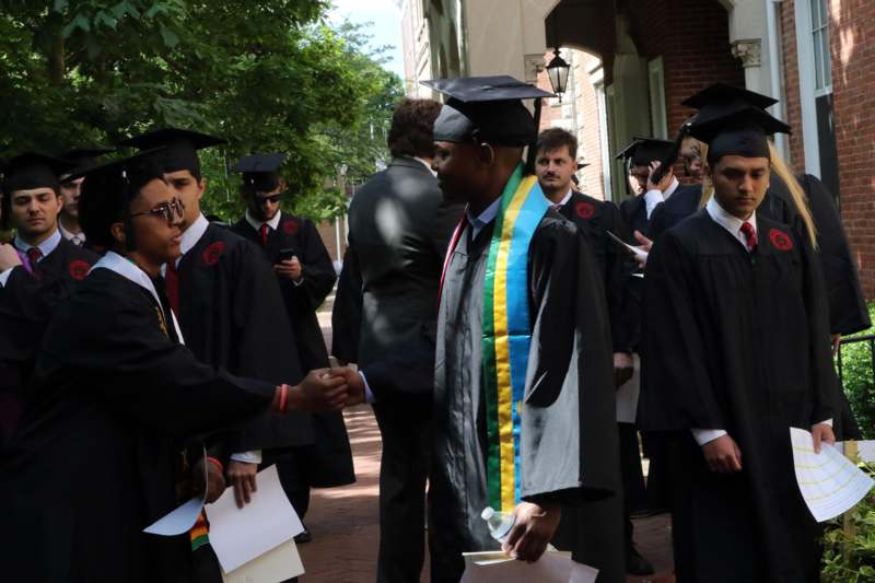 a group of people in graduation gowns shaking hands