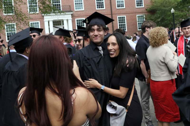 a man in a graduation gown hugging a woman